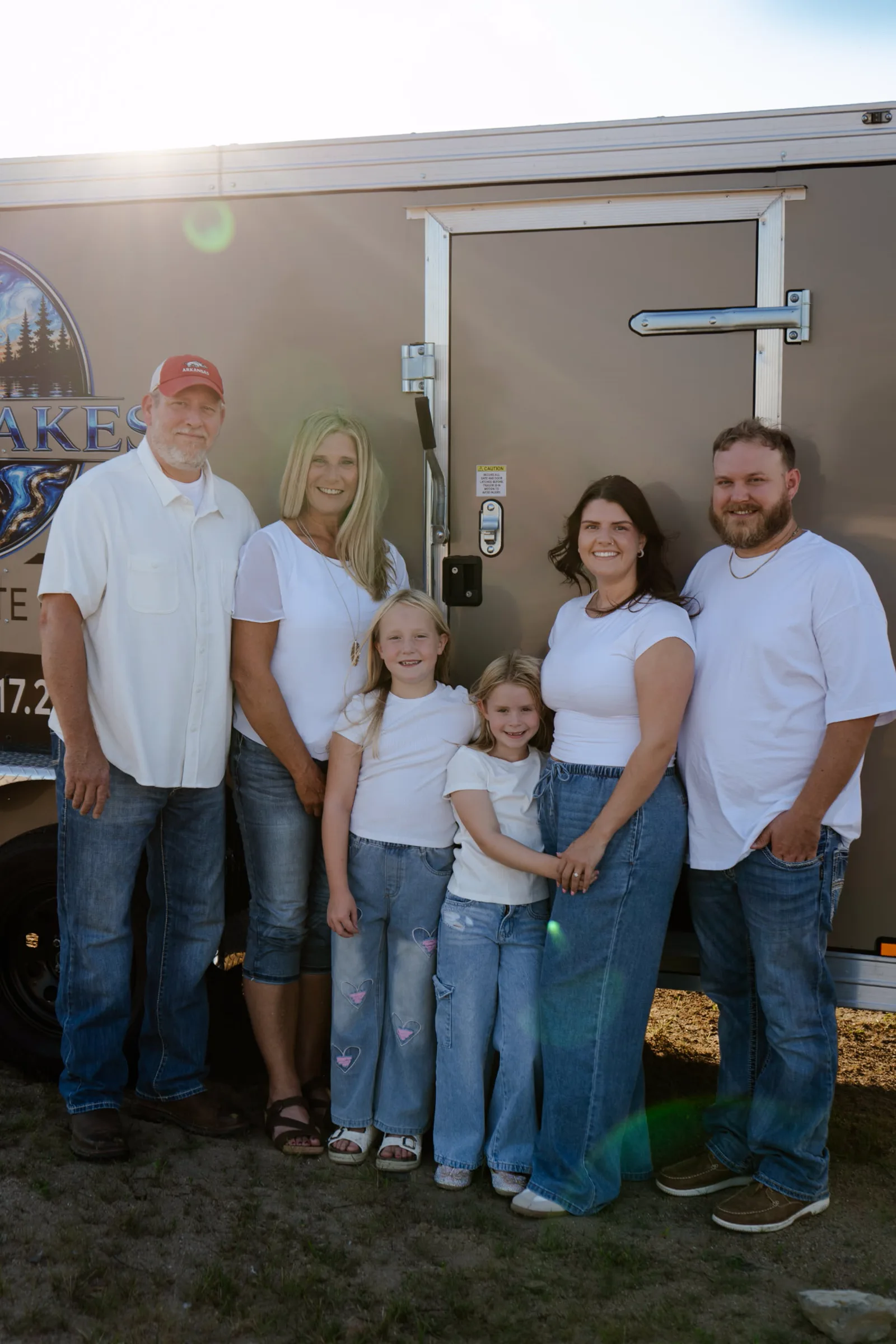 The Harrison and Barlow family standing together in front of the branded Twin Lakes Epoxy trailer