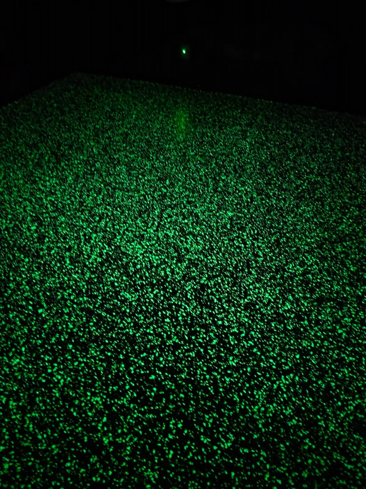 Neon-green glow-in-the-dark flake epoxy floor glowing in the dark in Rocking Chair Resort movie room, Mountain Home AR