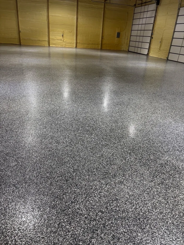 Finished black, white and gray full-flake epoxy floor in a large shop reflecting the overhead lights